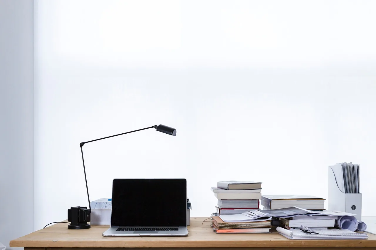 Bureau sobre avec une lampe, un ordinateur portable fermé et une pile de livres